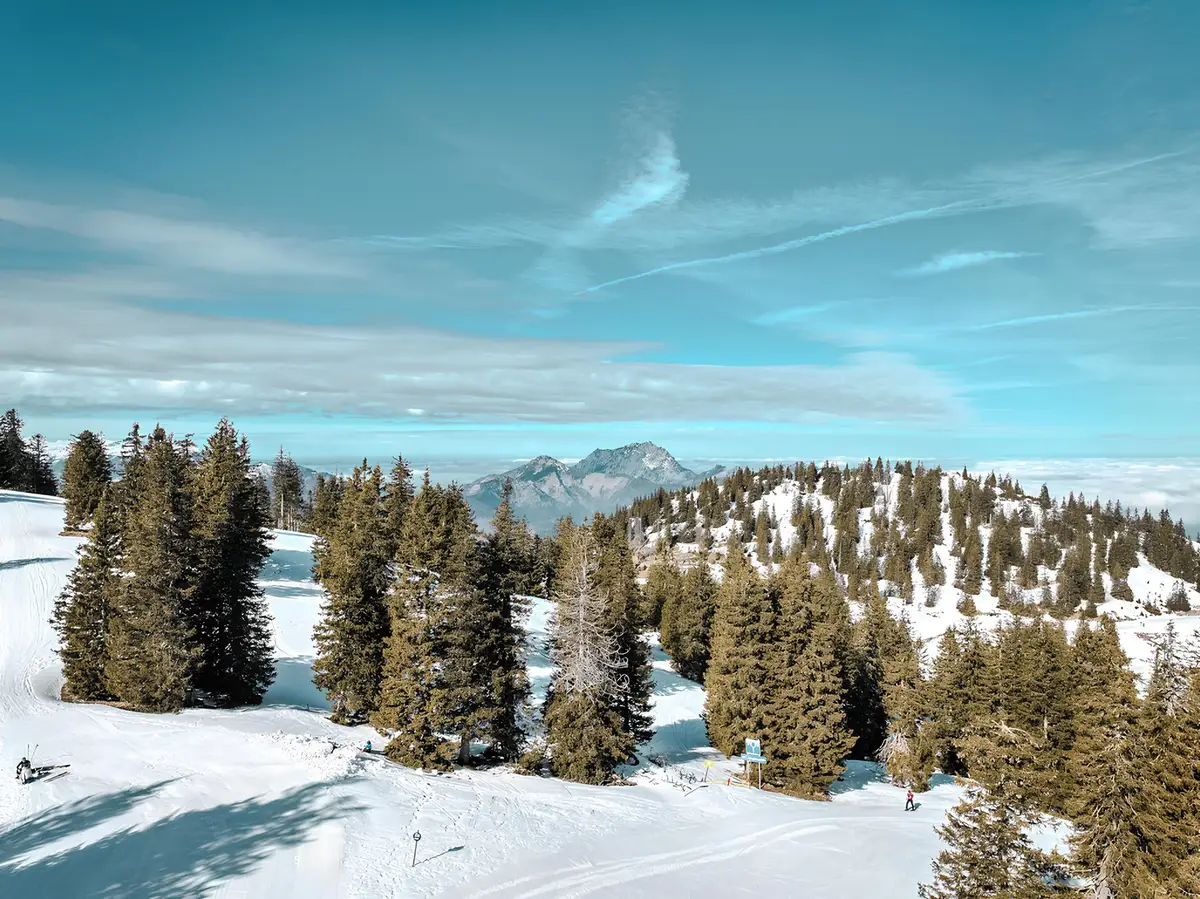 Esquiadores bajando por pistas nevadas en los Alpes suizos con teleféricos al fondo