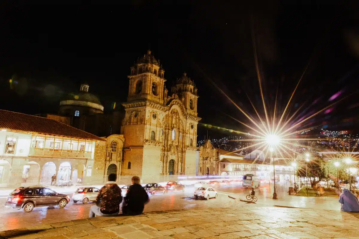 Plaza principal de un pueblo colombiano al atardecer con arquitectura colonial, montañas al fondo y gente disfrutando de