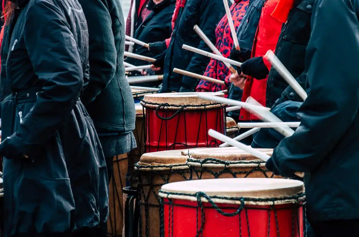 Instrumentos de percusión y tambores de candombe dispuestos en círculo sobre piso de madera