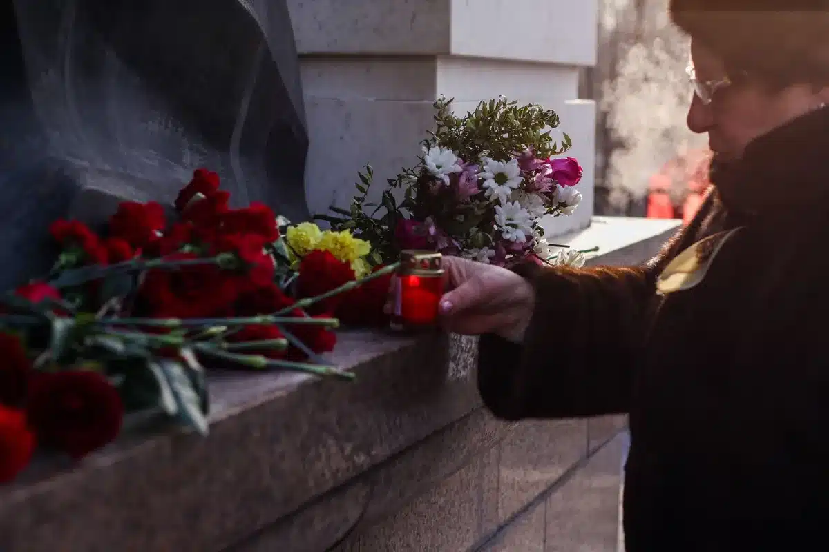 Ceremonia fúnebre en salón parlamentario con flores y asistentes