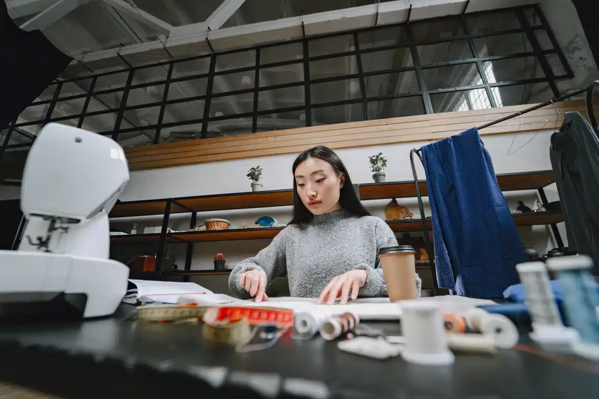 Estudio de diseño de moda con muestras de tela, herramientas artesanales y manos trabajando en un diseño