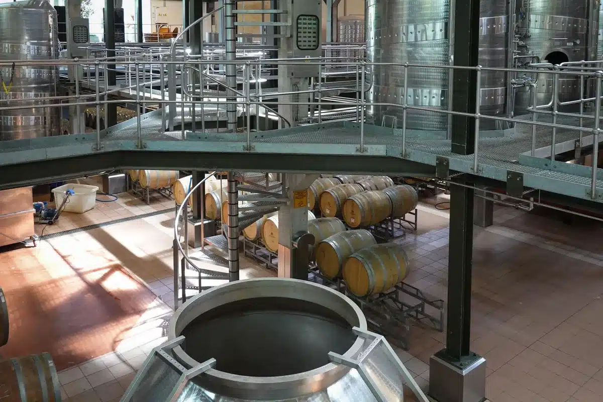 Trabajadores en línea de producción de cervecería industrial con tanques y maquinaria de envasado