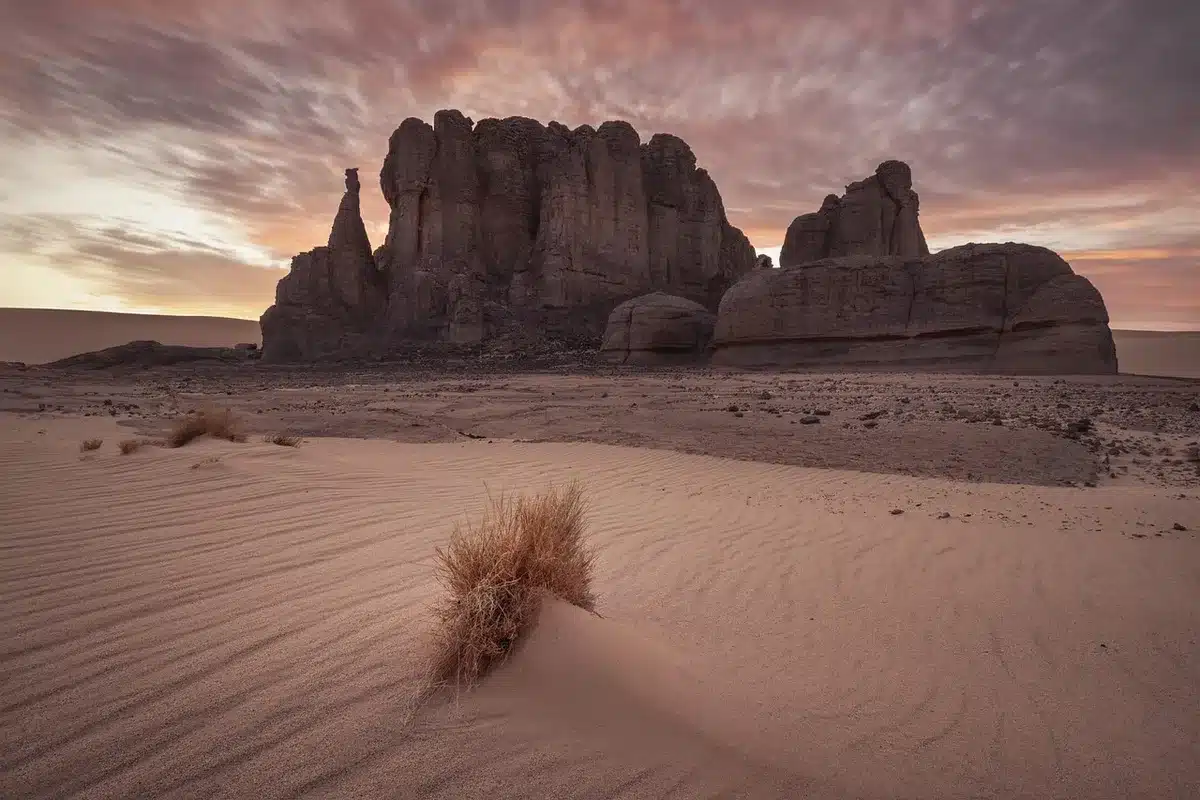 Dunas del desierto y pequeño grupo anónimo alrededor de una hoguera al atardecer